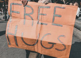 Man and Woman Holding Free Hugs Signage